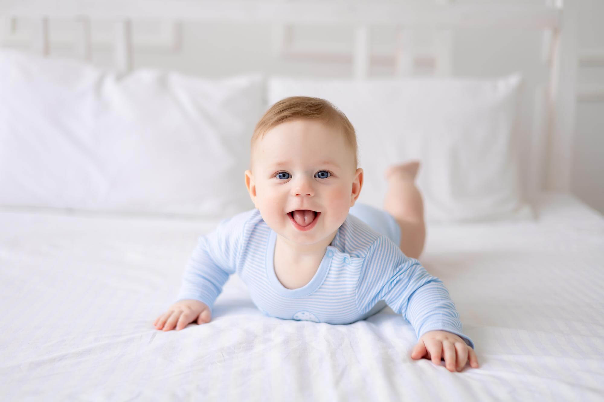 A cute healthy little baby is lying on a bed at home.