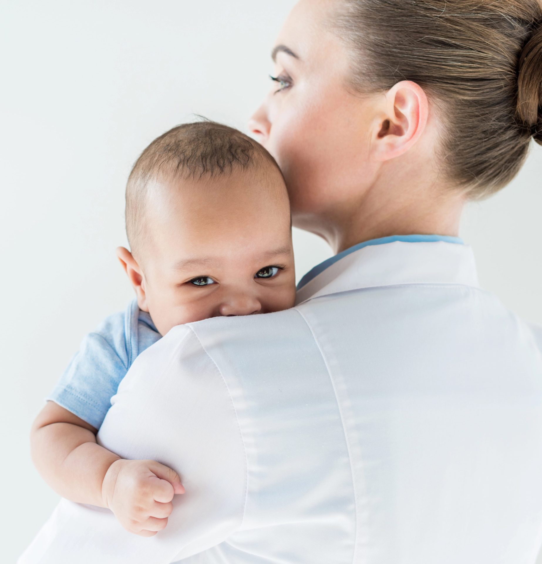 Medical professional holding a smiling child in her arms.