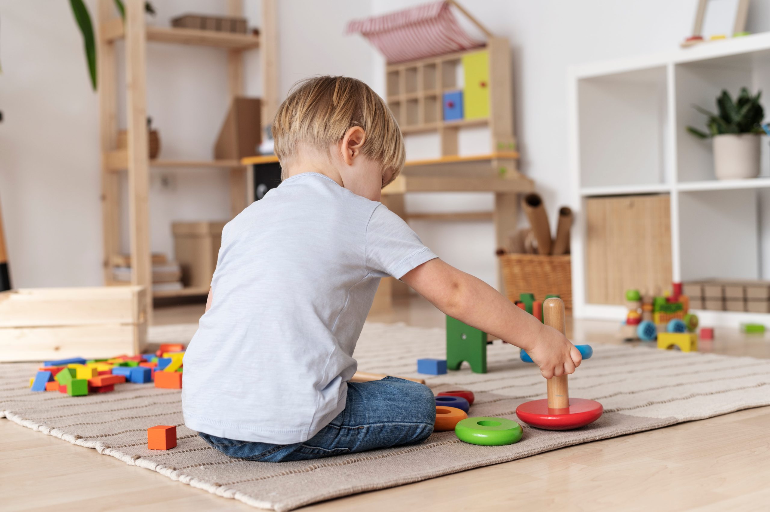 Young boy playing with colorful stacking rings and blocks.
