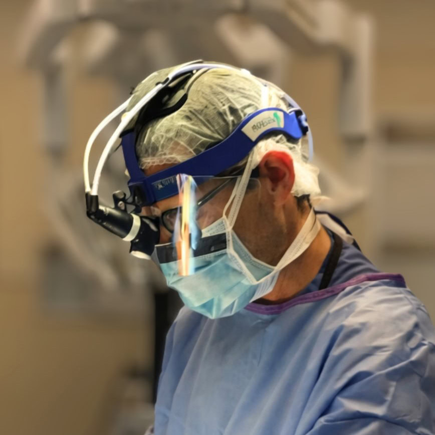 Surgeon wearing surgical mask and headlamp during operation.