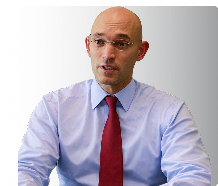 Bald man with glasses wearing a blue shirt and red tie.