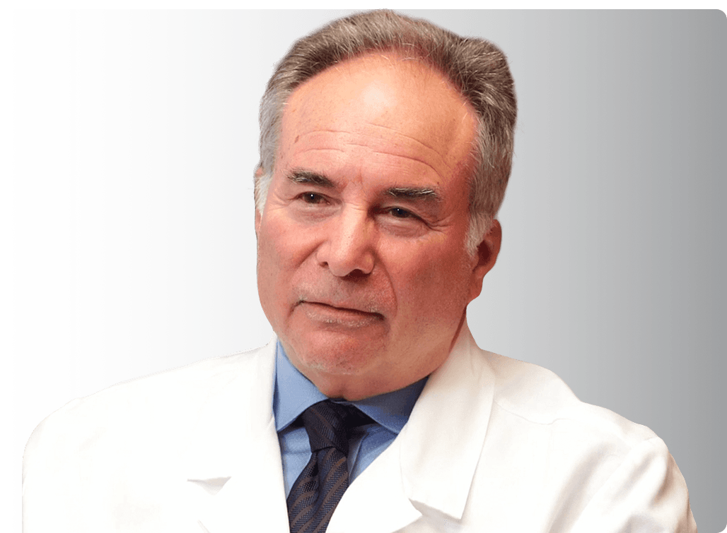 Portrait of Dr. Gregg Jacob in a white coat and blue shirt.