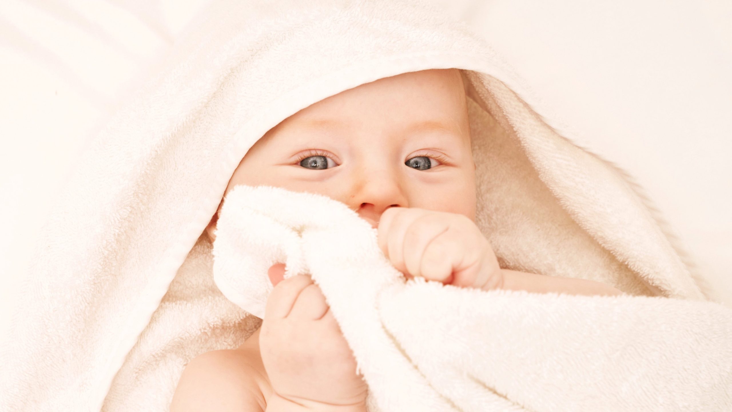 Baby with a cleft palate wrapped in a soft towel, looking curiously at the camera.