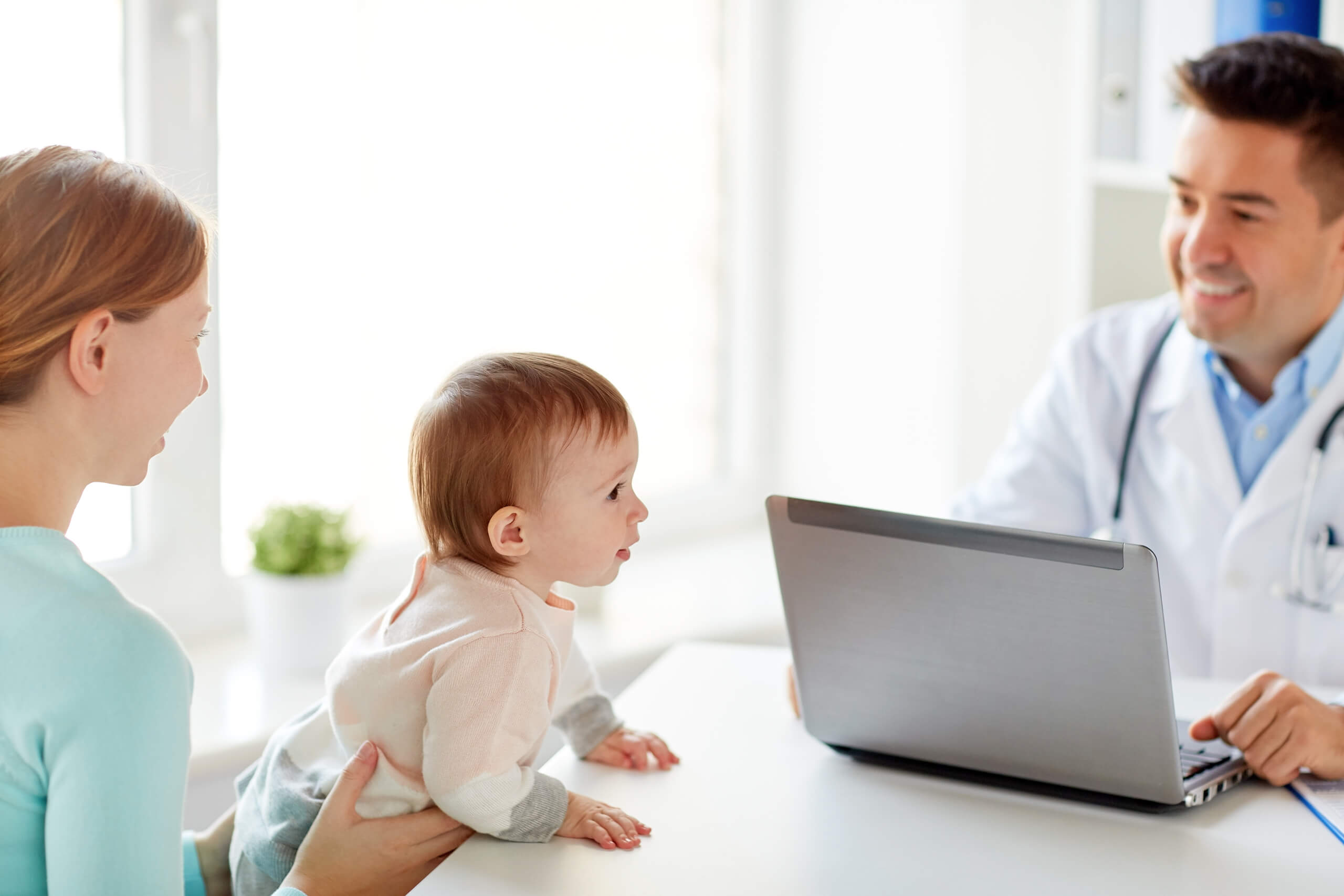 Mother with infant in doctor's office with smiling doctor