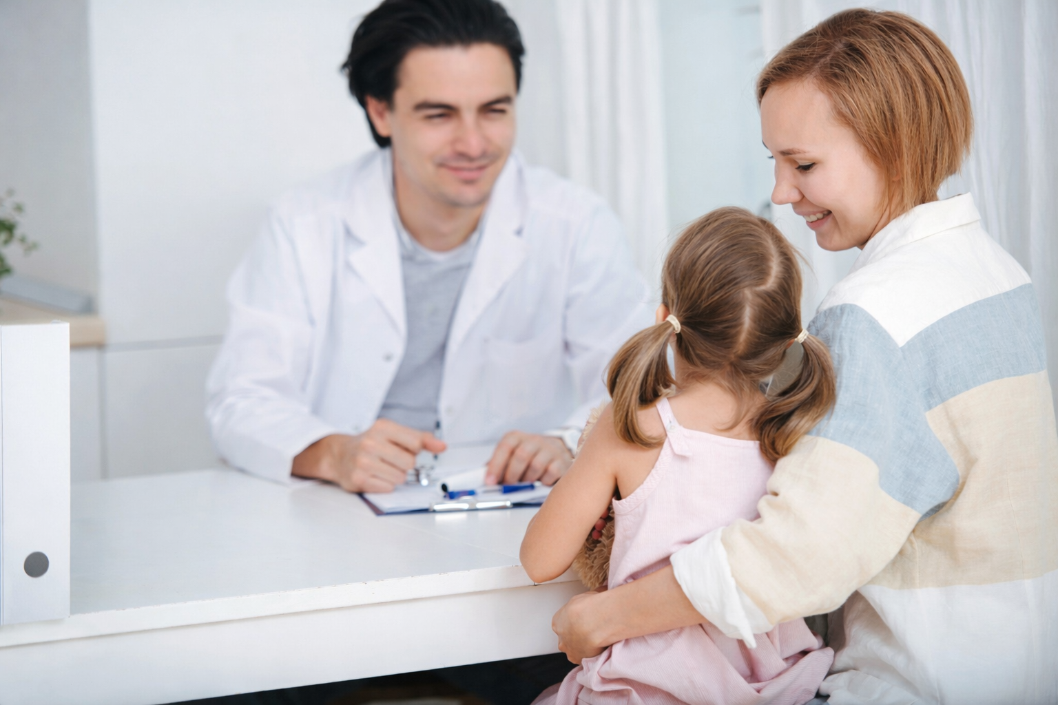 Doctor consulting with mother and young girl in a medical office setting.