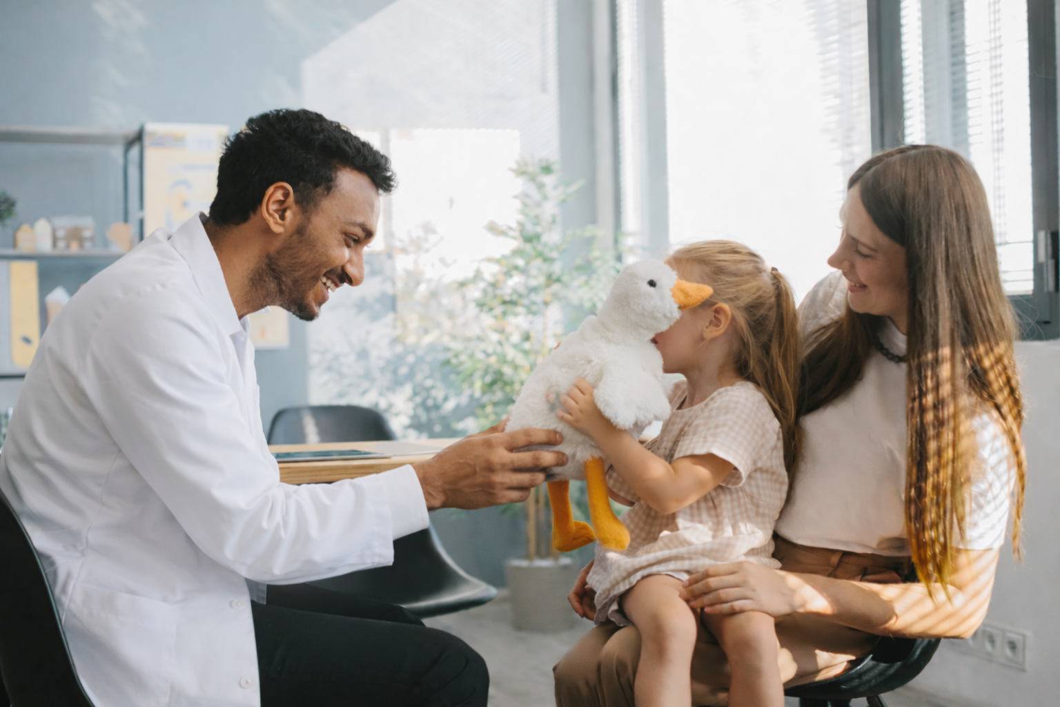 Dentist and young girl with teddy bear during dental check-up.