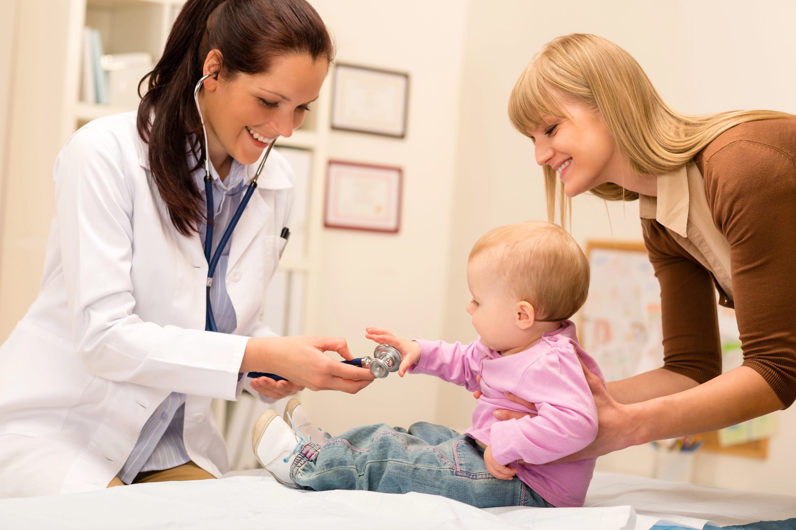 Clinician engages with a young child during a follow-up visit while the child's mother provides support.
