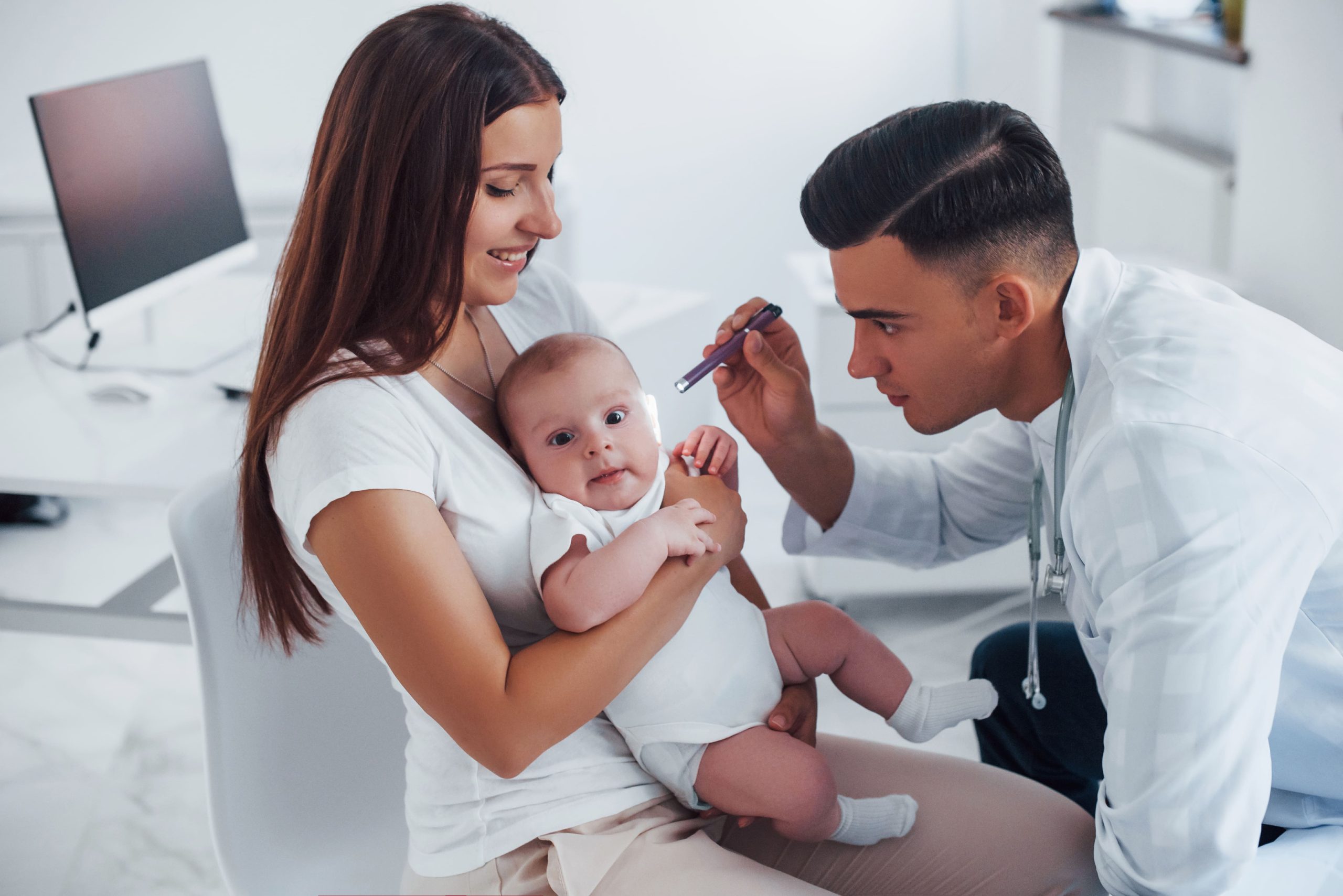 peditrician examining baby held by mother