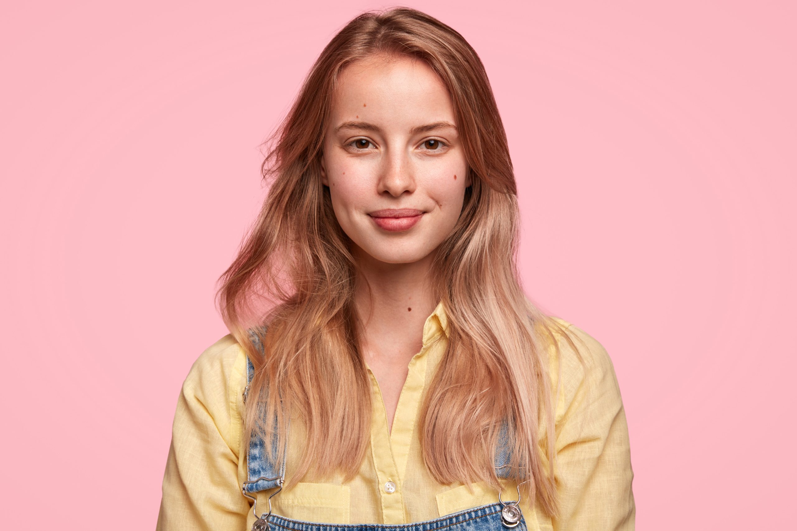 Pretty young girl with blonde hair and pink background.
