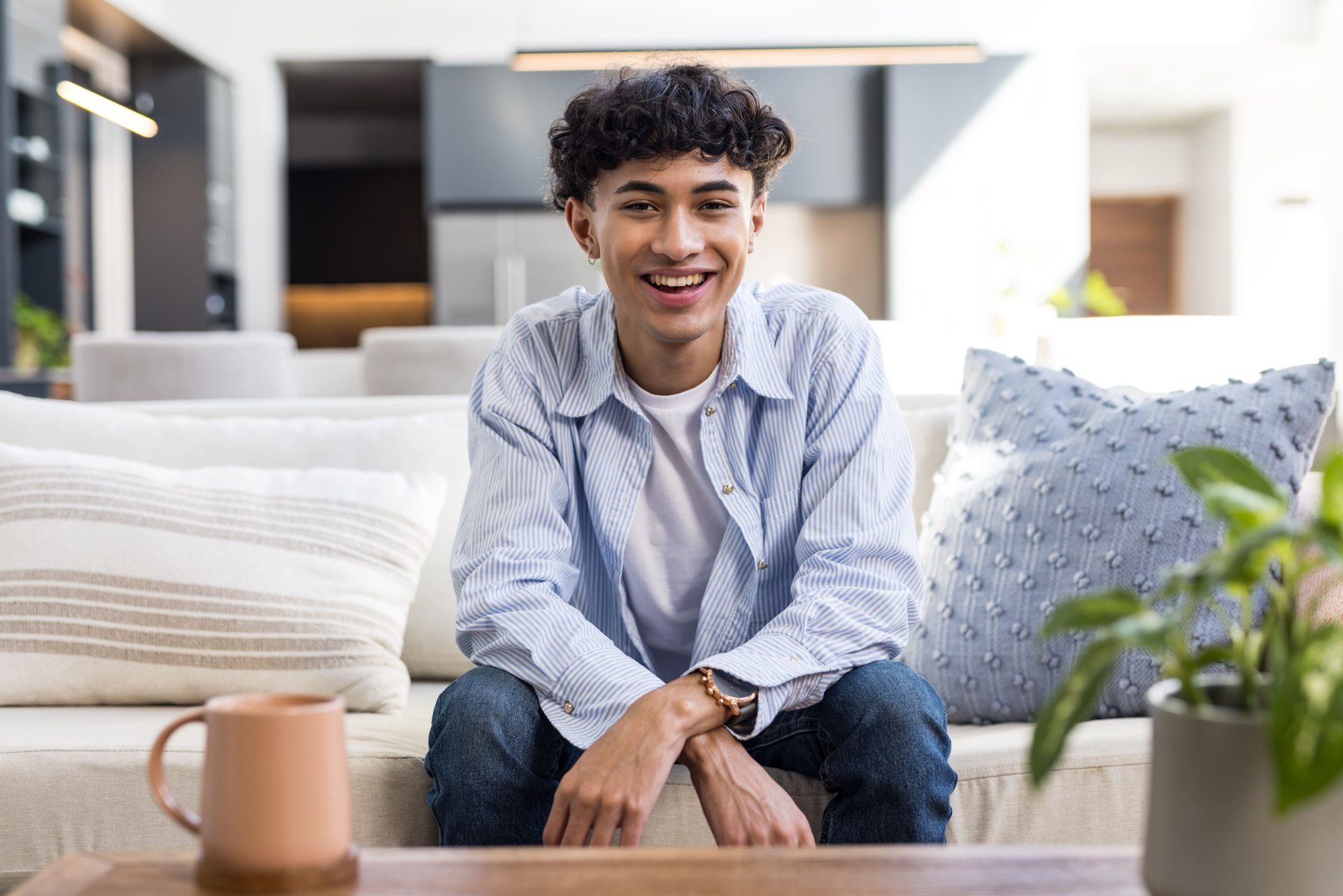 Smiling teenage boy sitting couch home feeling relaxed happy.