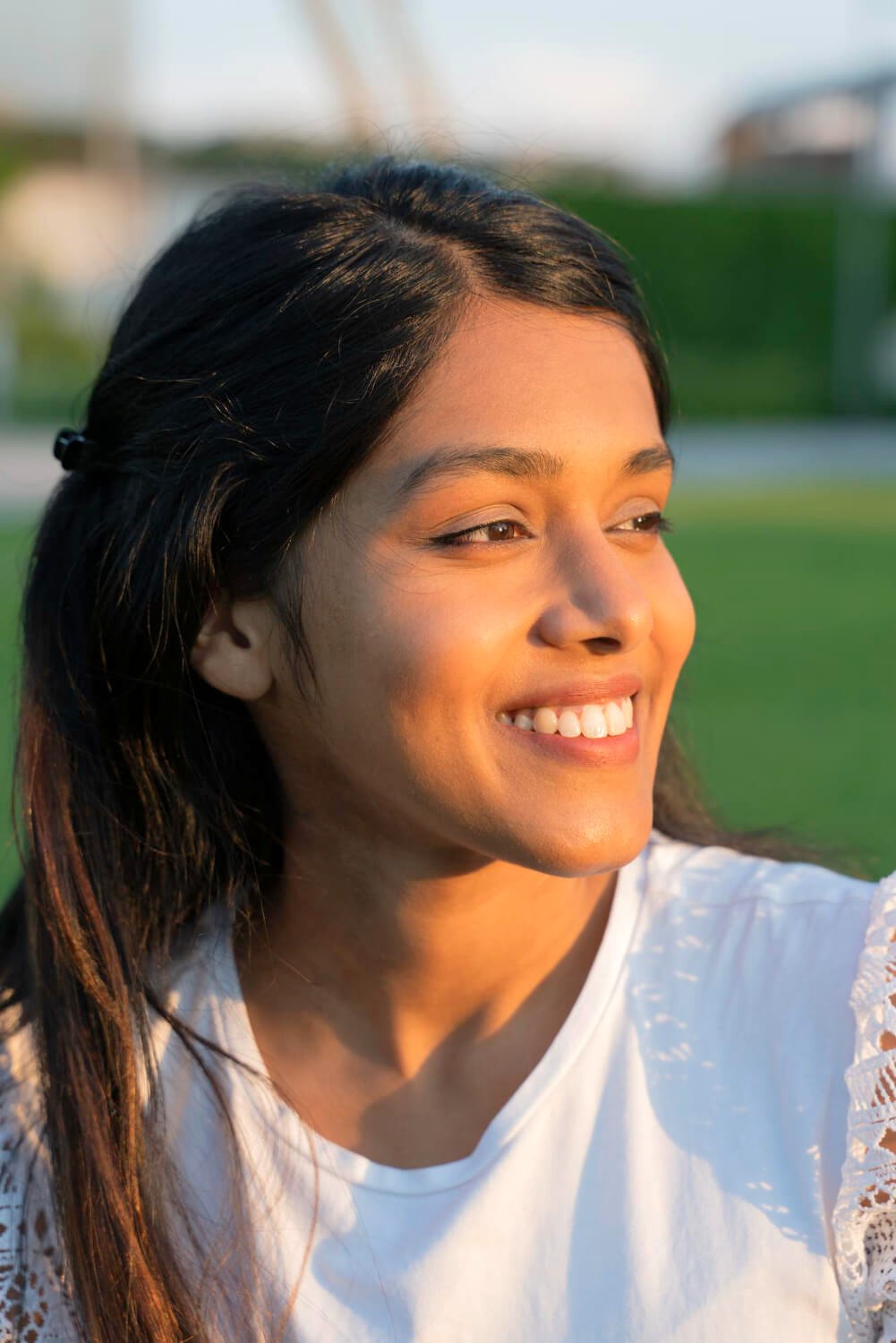 Happy woman with long dark hair smiling in sunlight.
