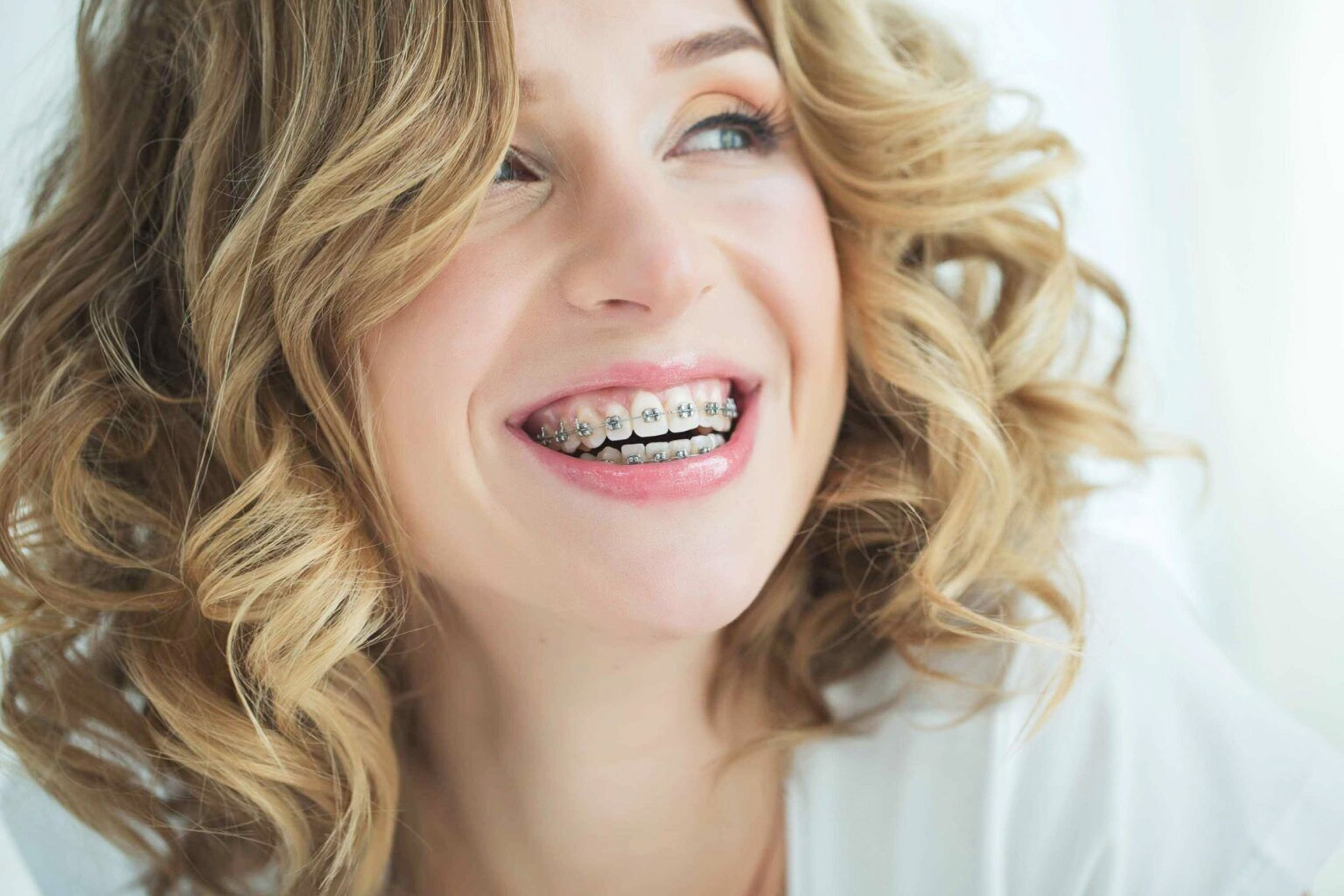 Smiling young woman with curly blonde hair and braces