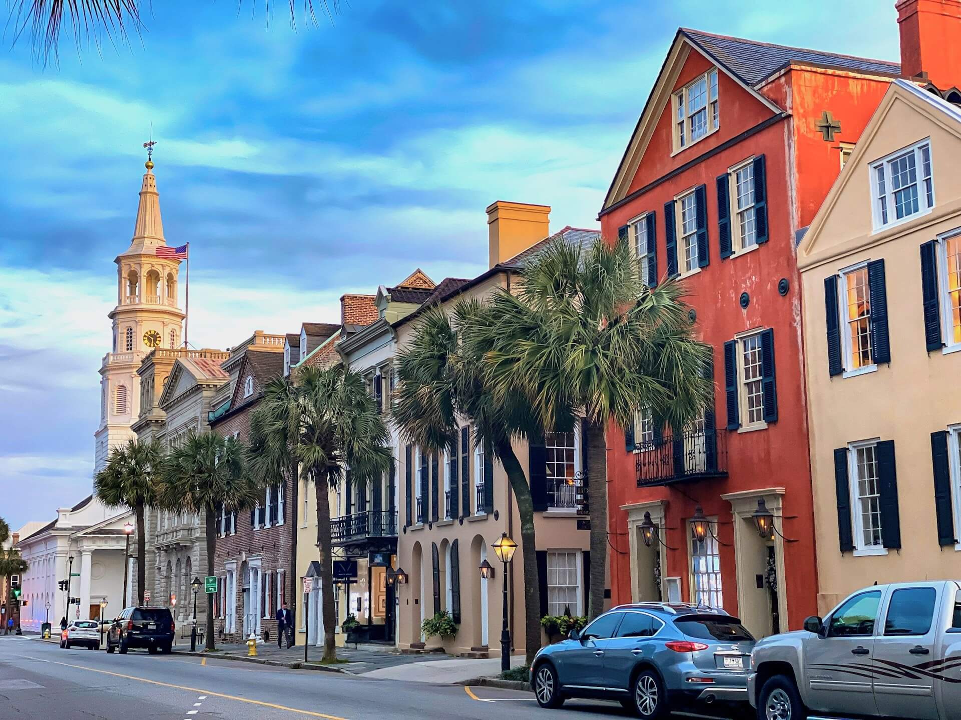 Colorful historic buildings and palm trees on a sunny street in Charleston, South Carolina.