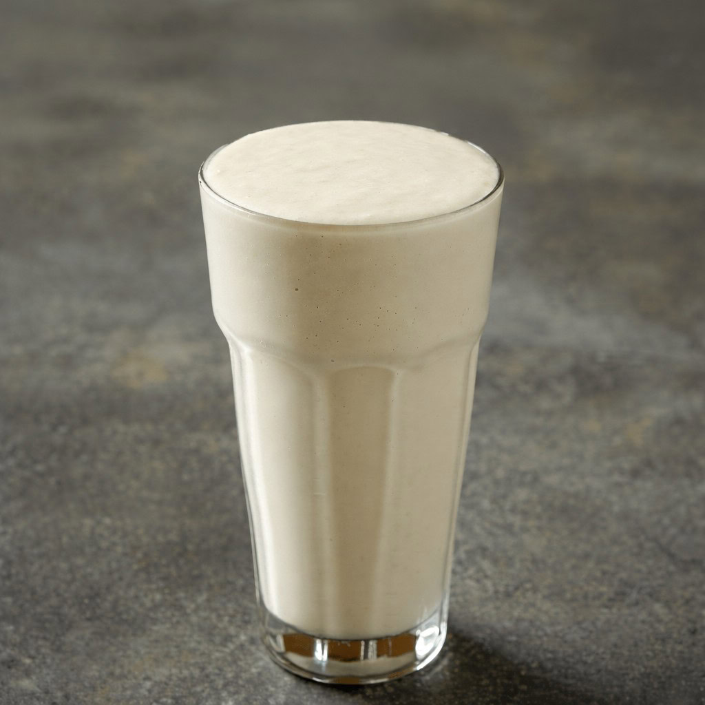 Glass of creamy liquid diet drink on a dark surface.
