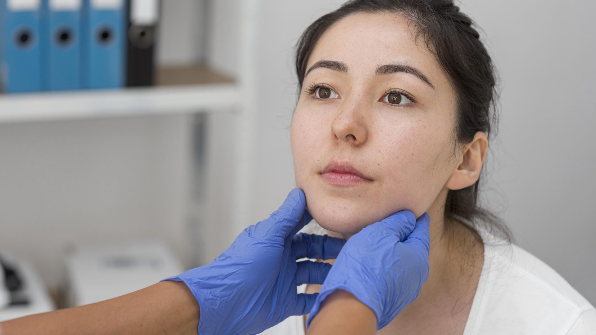 Young woman getting facial exam in doctor's office.