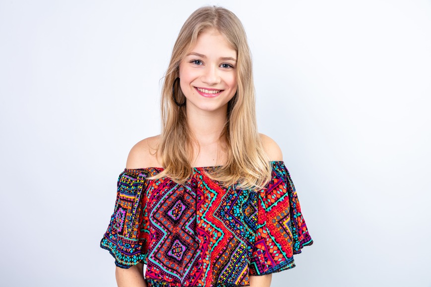 smiling-young-blonde-woman Young woman with blonde hair smiling, wearing a vibrant patterned top.